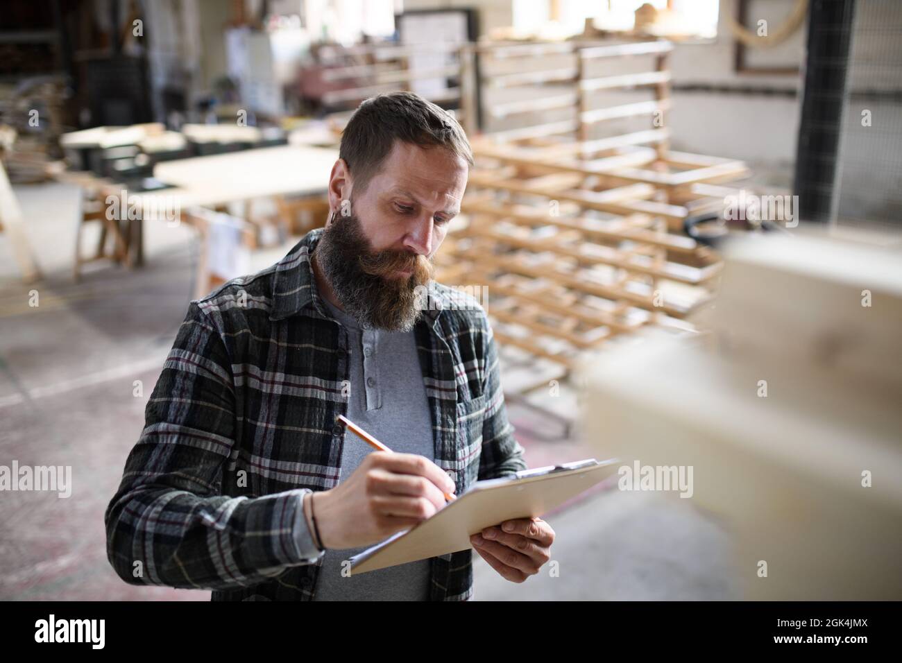 Porträt eines reifen männlichen Zimmermanns, der in Innenräumen in der Tischlerei die Gestaltung seines Produkts skizziert. Konzept für kleine Unternehmen. Stockfoto