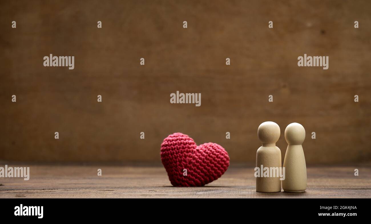 Paar hölzerne Männer der Braut und des Bräutigams, rotes Herz, brauner Hintergrund, Konzept der Liebe und Beziehungen. Tempo der Polizei Stockfoto