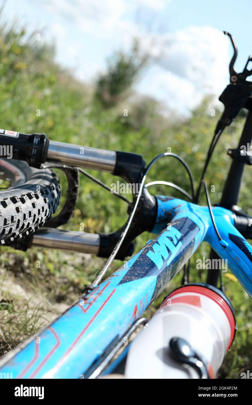 GÖTTINGEN, DEUTSCHLAND - 20. Aug 2021: Vertikale Nahaufnahme eines blauen Mountainbikes, das mit einer Plastikwasserflasche im Gras liegt. Outdoor-Sport in Germa Stockfoto