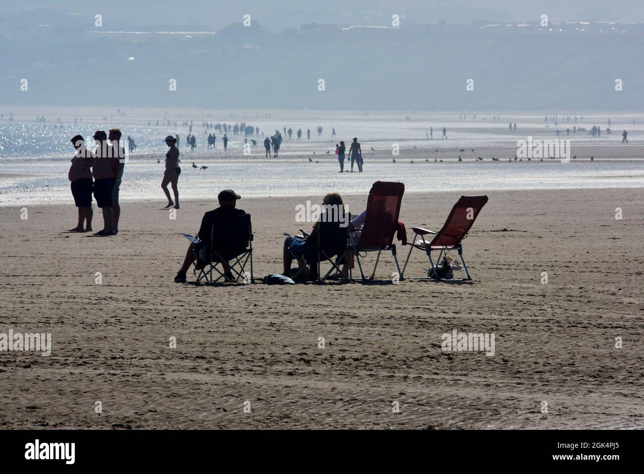 In der Sonne sitzend, Filey Beach, North Yorkshire Ostküste, beschäftigt mit Urlaubern, Nordengland, Großbritannien Stockfoto