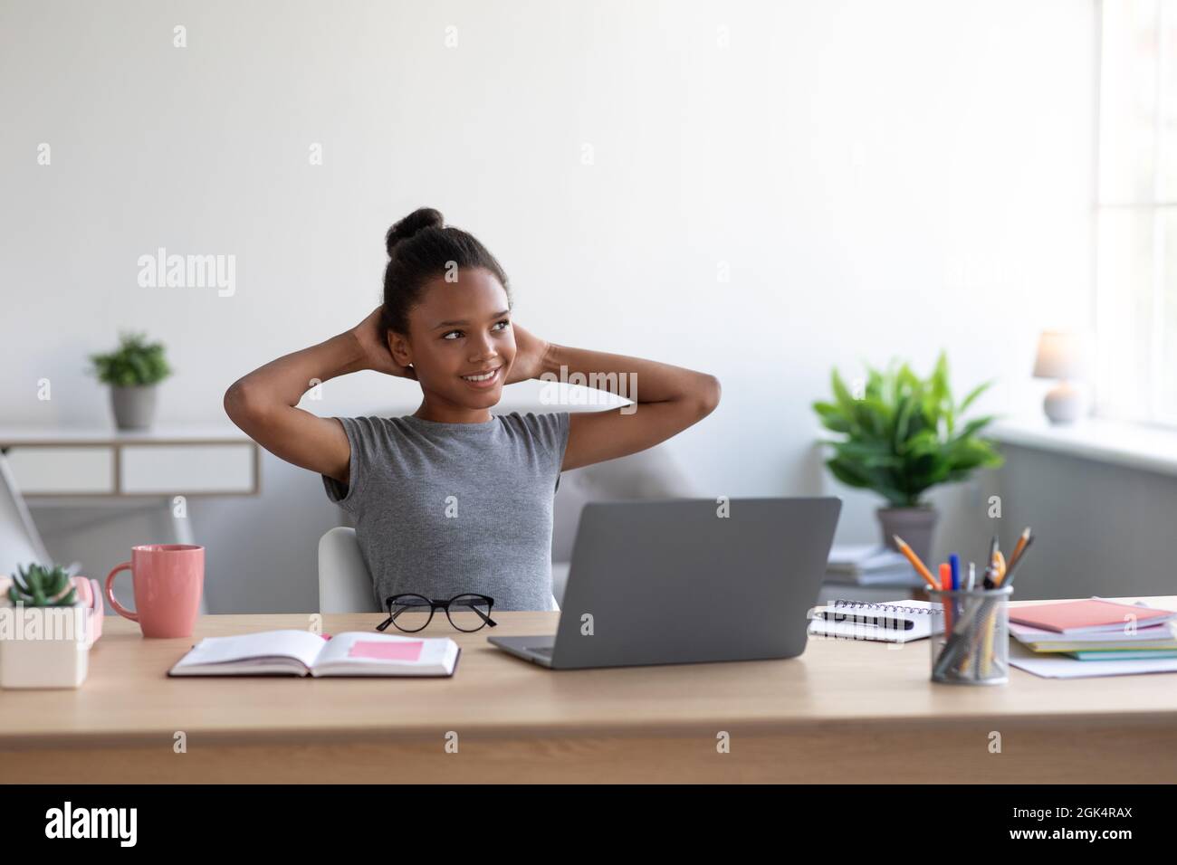 Fröhliche Teenager afroamerikanische Frau, Schulmädchen, die zu Hause mit Laptop studiert, ausruhen, eine Pause vom Unterricht nehmen Stockfoto