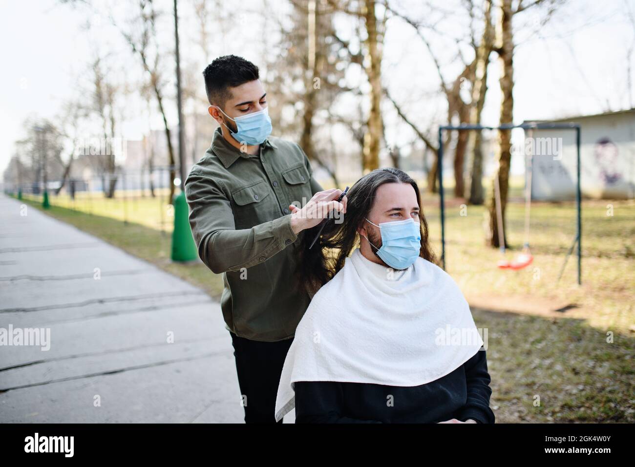 Haarschnitt vor Wohnblock auf Hof, Coronavirus und Lockdown-Konzept. Stockfoto