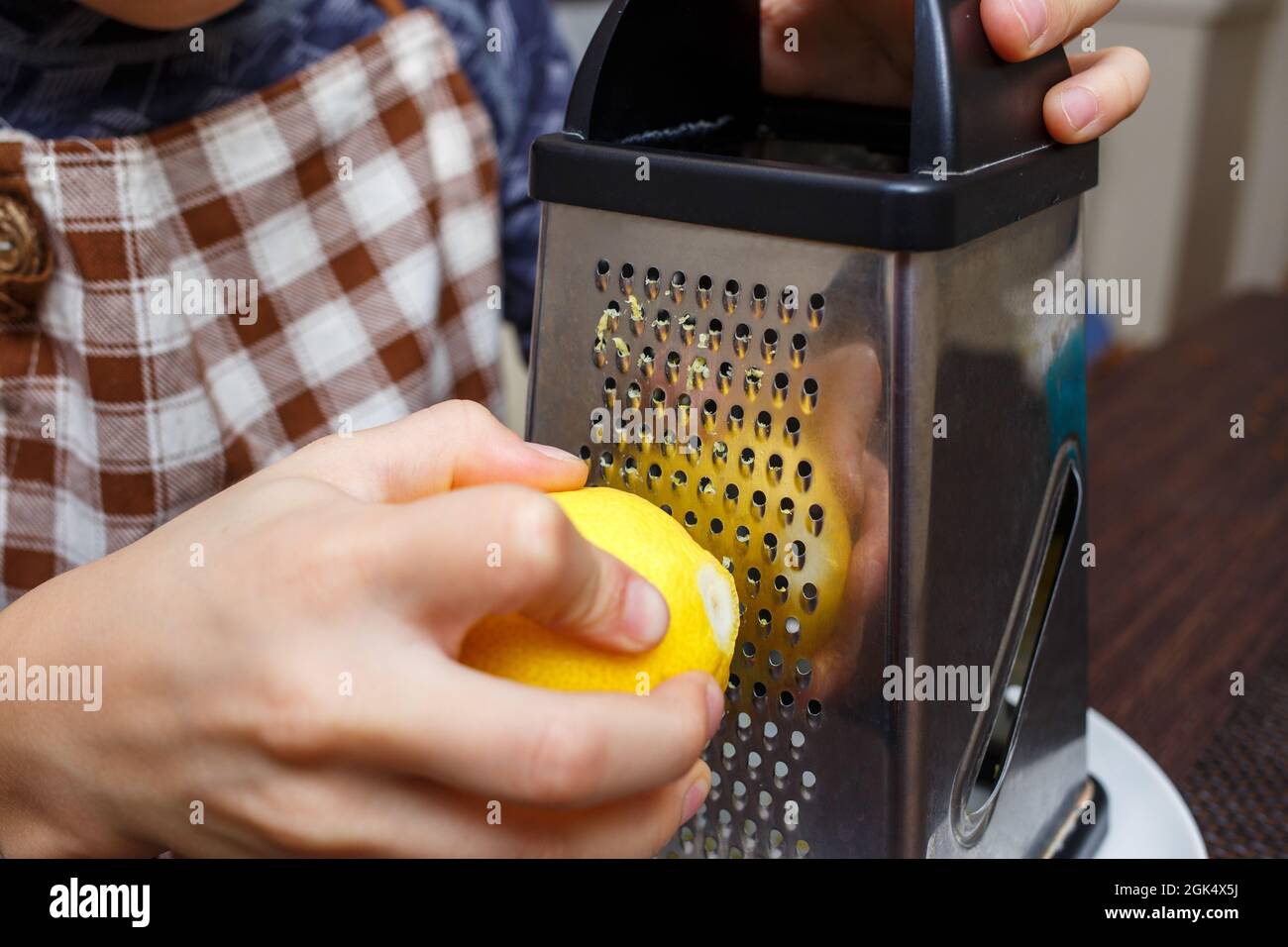 Kleiner Junge, der Zitrone mit Reibe in der heimischen Küche zesting. Kochen zu Hause lernen Kind Stockfoto