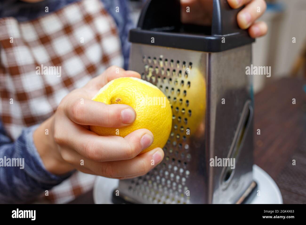 Kleiner Junge, der Zitrone mit Reibe in der heimischen Küche zesting. Kochen zu Hause lernen Kind Stockfoto