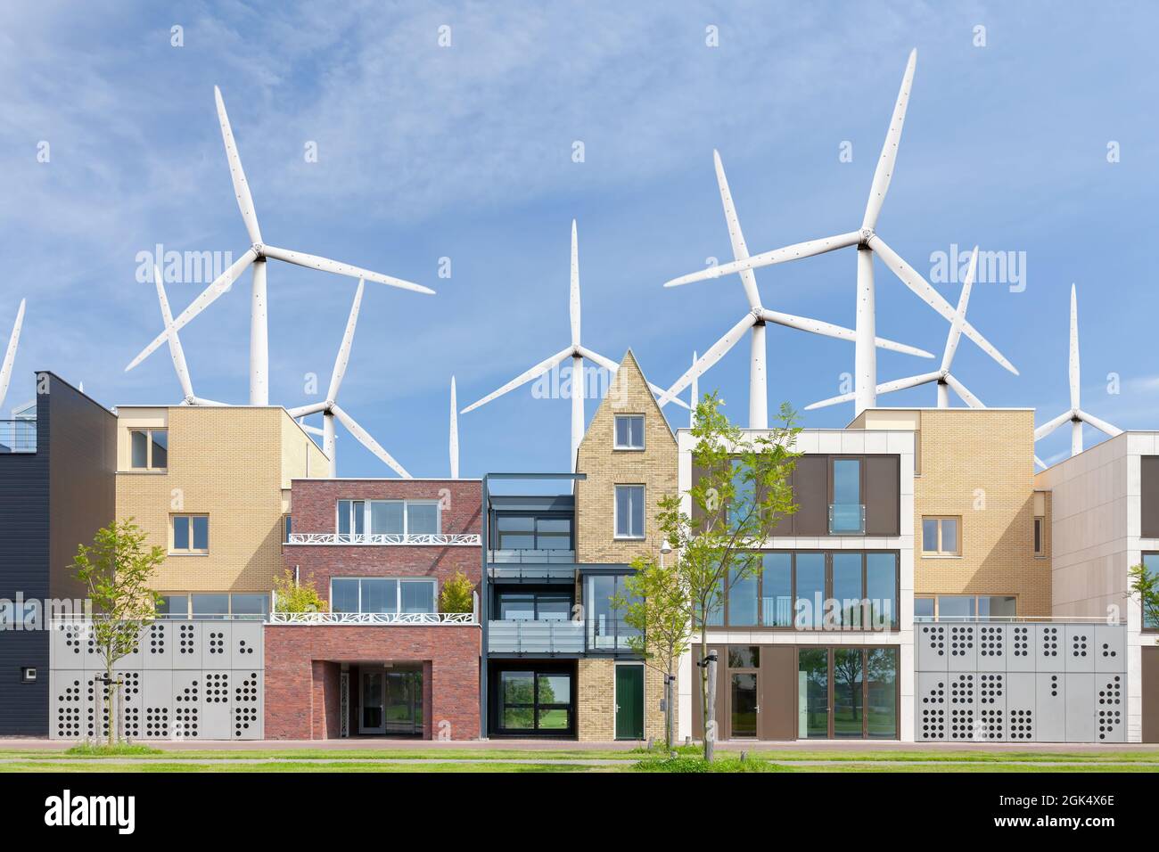 Reihe neuer, moderner niederländischer Familienhäuser vor einem Feld mit großen Windturbinen Stockfoto