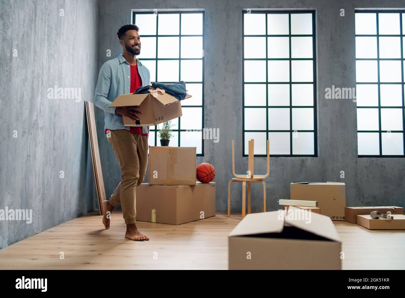 Glücklicher junger Mann mit Packkisten, Umzug nach Hause, neues Wohnkonzept. Stockfoto