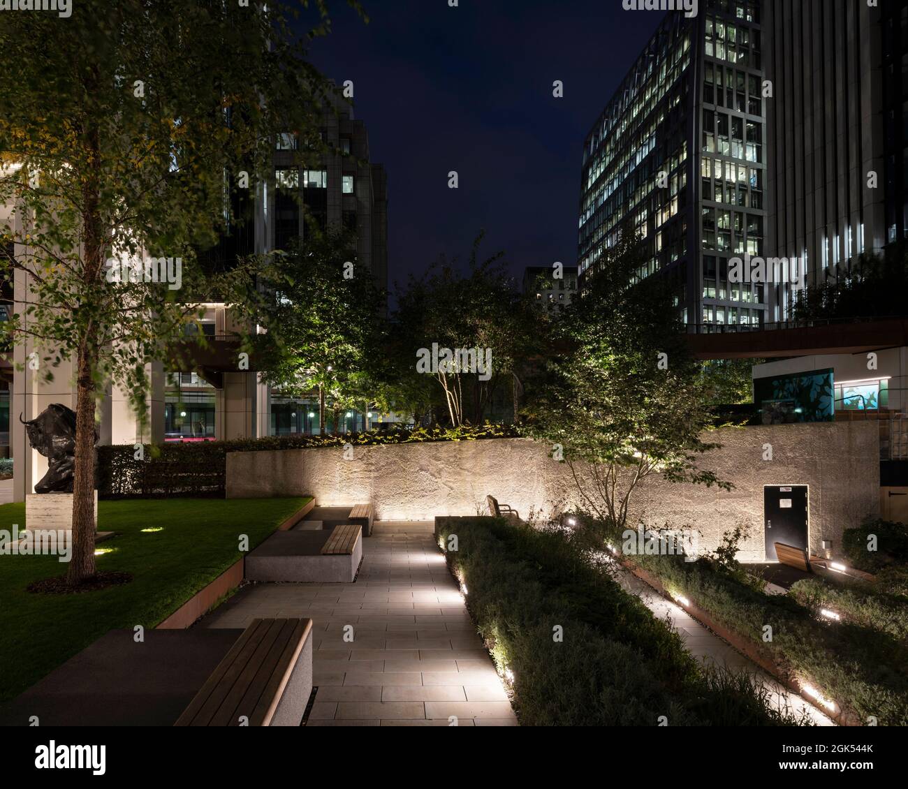 Salters' Garden bei Nacht mit Landschaftsgestaltung und Beleuchtung mit City Behind. London Wall Place, London, Großbritannien. Architekt: Make Ltd, 2019. Stockfoto