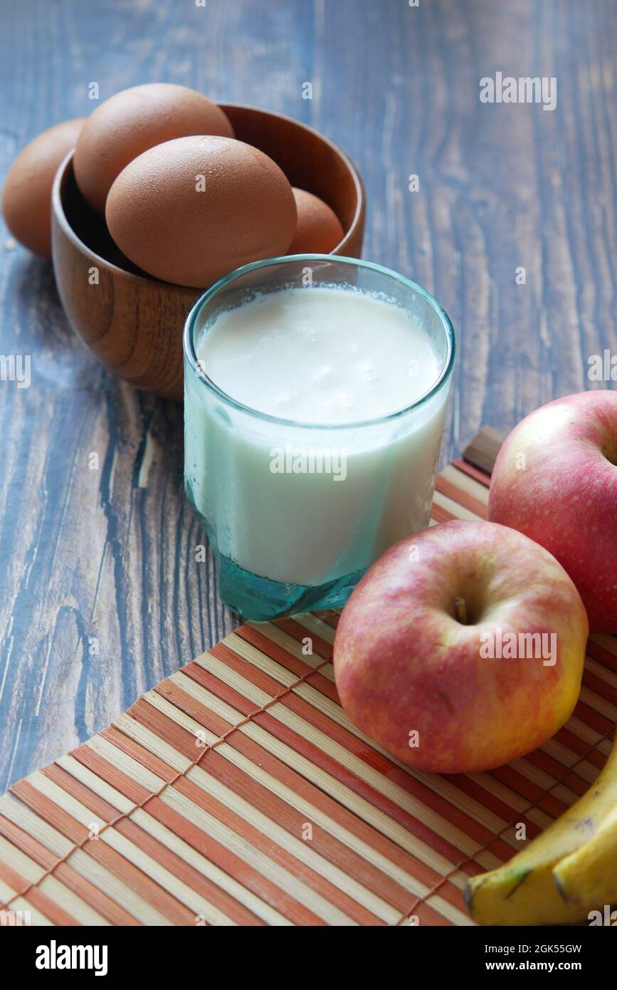 Gesundes Snackkonzept mit Milch, Ei und Apfel auf dem Tisch. Stockfoto