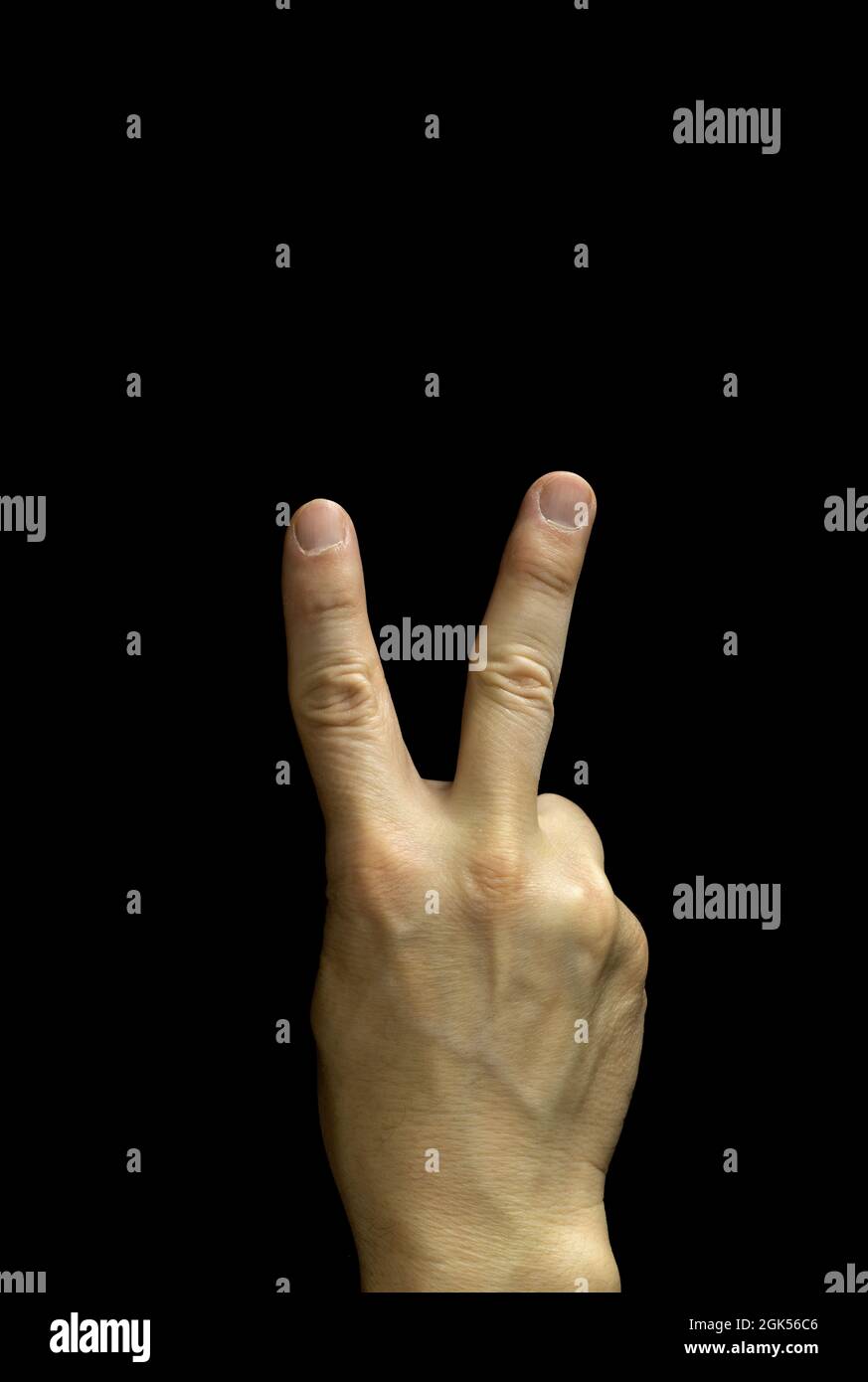 Eine männliche Hand, die mit den Fingern das Siegeszeichen macht, angeordnet im Buchstaben V, schwarzer Hintergrund Stockfoto
