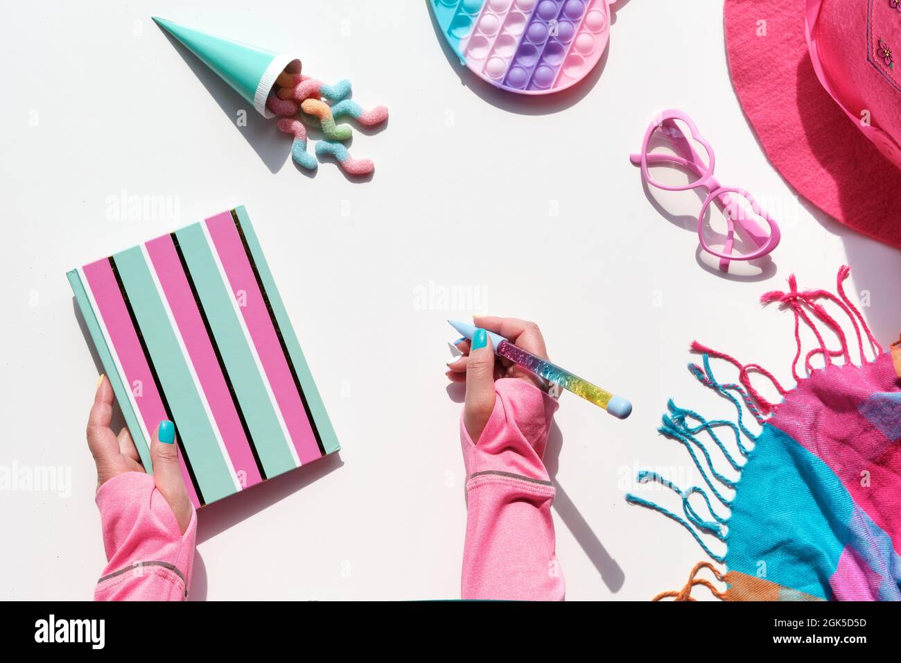 Sammlung von Party-Objekte und Süßigkeiten auf geometrischem Papier flach legen. Schokolade, Süßigkeiten. Notizbuch und Regenbogenstift in der Hand. Geometrischer Hintergrund mit Ebenen Stockfoto