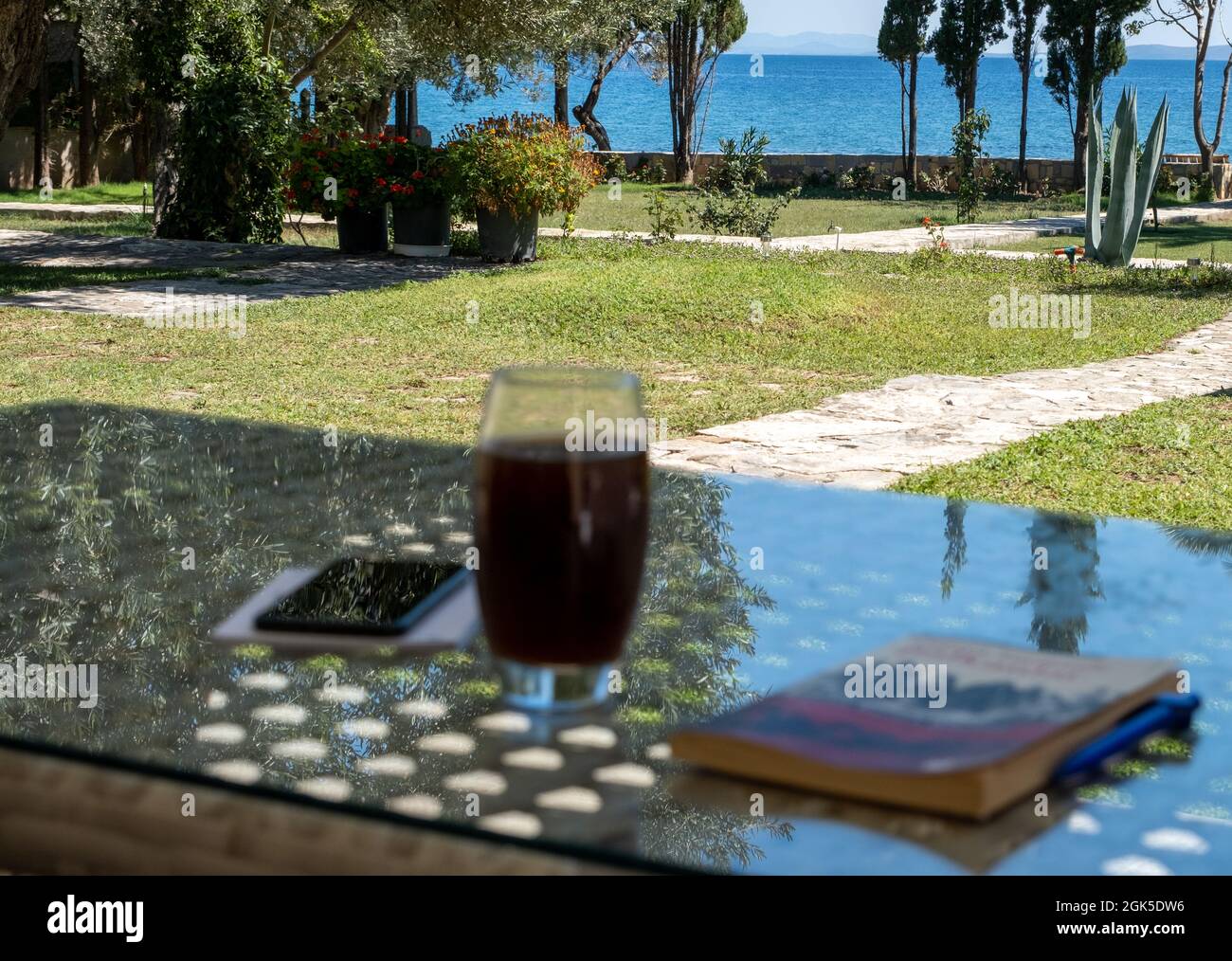 Zeit im Sommerhaus in der Nähe des Strandes, Lesen und Trinken am Meer zu Hause Stockfoto