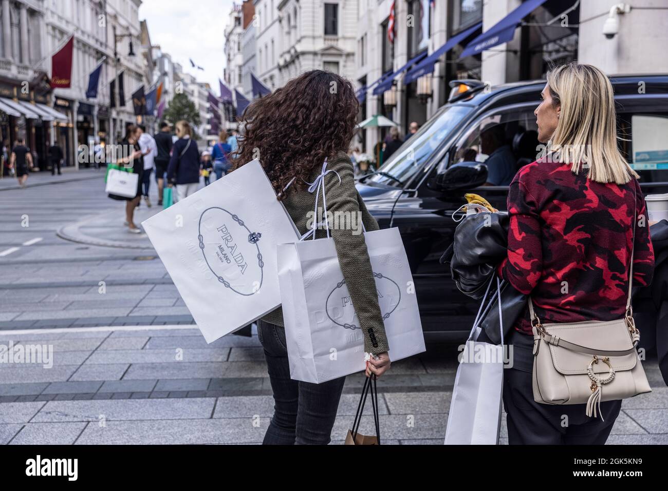 Käufer von Luxusmarken, die PRADA-Taschen in der Old Bond Street, London, England, Großbritannien, tragen Stockfoto