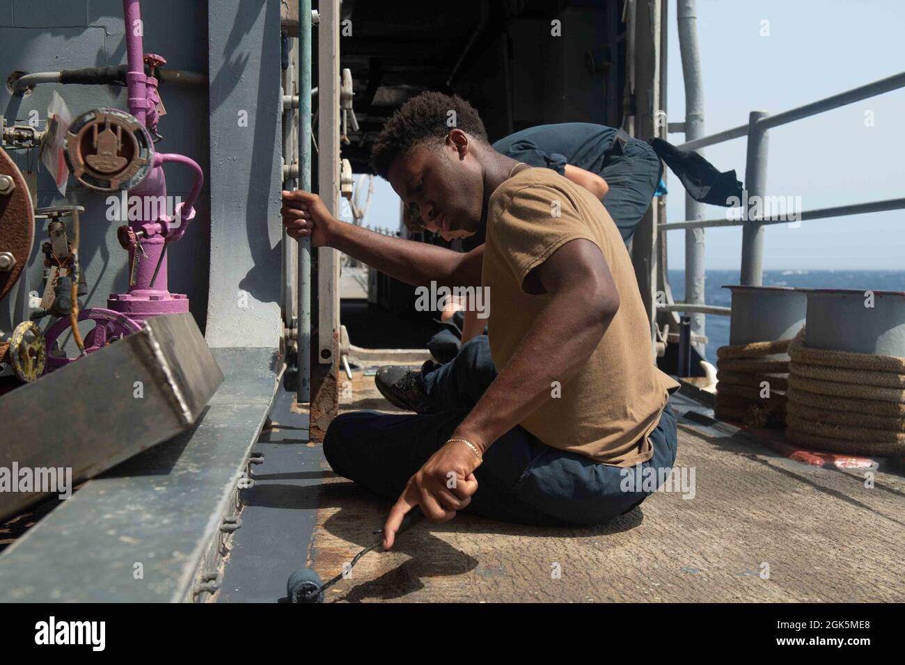 210809-N-WQ732-2002 ROTES MEER (9. August 2021) – Seaman Amari Morgan malt das Wetterdeck des Lenkraketen-Kreuzers USS Monterey (CG 61) im Roten Meer, 9. August. Monterey wird in den Einsatzbereich der 5. US-Flotte eingesetzt, um Marineinteraktionen zu unterstützen, um die maritime Stabilität und Sicherheit in der Zentralregion zu gewährleisten und das Mittelmeer und den Pazifik durch den westlichen Indischen Ozean und drei strategische Engpässe zu verbinden. Stockfoto
