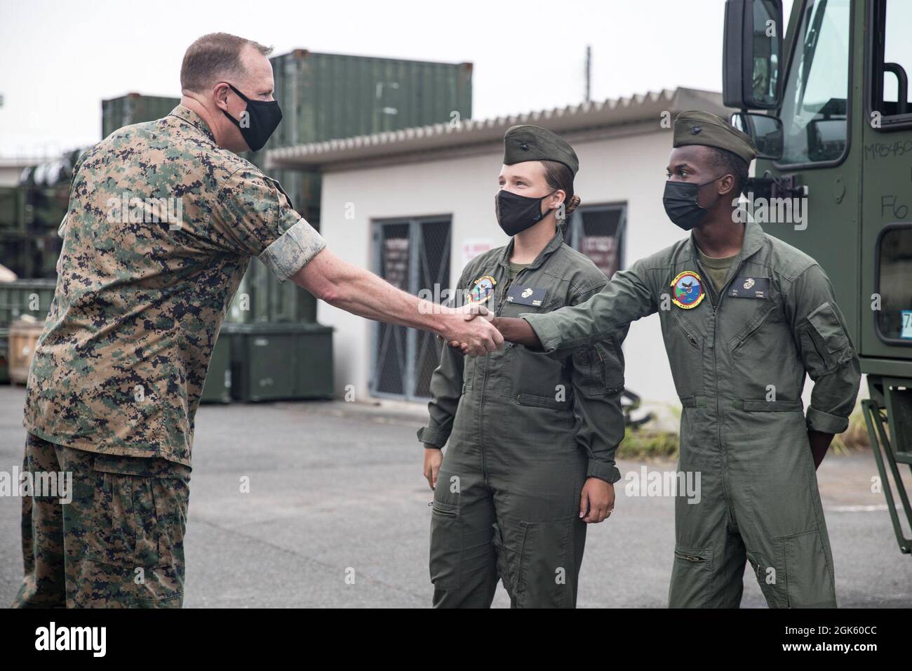 U.S. Marine Corps CPL. Kevon Cooke, ein Spezialist für Einsatzfeuerwehr und Rettung bei Marine Wing Support Squadron 171, schüttelt sich bei einem Besuch der Marine Corps Air Station Iwakuni, Japan, am 11. August 2021 die Hände mit LT. Gen. Wise, dem stellvertretenden Kommandanten für die Luftfahrt. Wise besuchte die Marine Aircraft Group 12, um im Rahmen von Force Design 2030 die aktuellen und zukünftigen Entwicklungen der Marine Corps-Luftfahrt zu diskutieren. Stockfoto