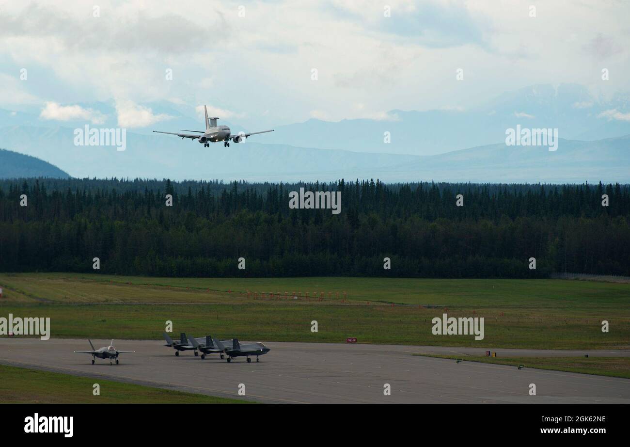 Eine Wedgetail der Royal Australian Air Force E-7A bereitet sich auf die Landung vor, während die US Air Force F-35A Lighting IIS sich auf den Start auf der Eielson Air Force Base, Alaska, vorbereiten, 11. August 2021. RAAF-Mitarbeiter besuchten Alaska zuletzt im Jahr 2019, um an der RF-A 19-3 teilzunehmen, bevor der 354. Kampfflügel seine ersten F-35As akzeptierte. Dieses Mal brachten die Australier ihre eigenen F-35As sowie EA-18G Growlers und einen E-7A Wedgetail mit, um Luft-Luft-Kämpfe sowie Cyber- und Nachrichtenfunktionen zu trainieren. Stockfoto