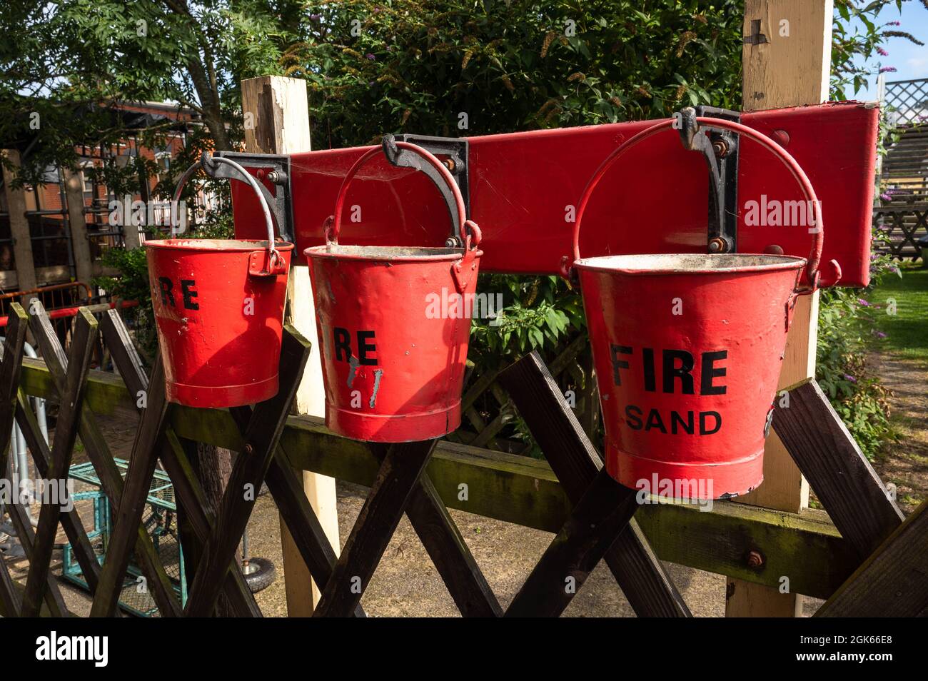 Weyborne Station Norfolk, drei rote Feuereimer mit Sand, die im Notfall an einem Zaun aufgehängt wurden Stockfoto