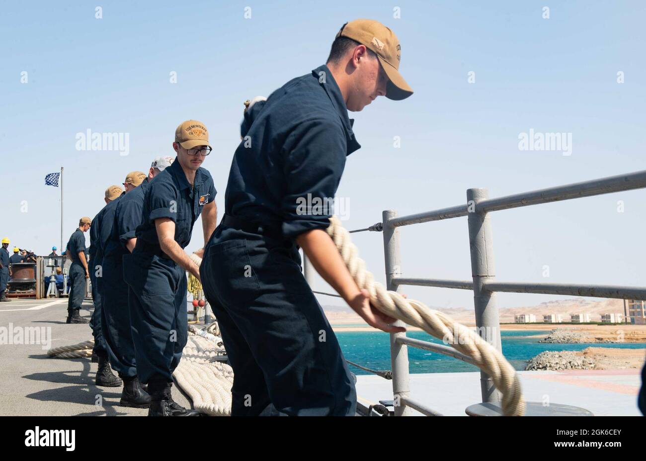 210814-N-WQ732-1010 BERENICE, Ägypten (14. August 2021) – Seeleute nehmen an Bord des Lenkraketen-Kreuzers USS Monterey (CG 61) eine Anlegestelle an, während das Schiff Berenice, Ägypten, am 14. August verlässt. Monterey wird in den Einsatzbereich der 5. US-Flotte eingesetzt, um Marineinteraktionen zu unterstützen, um die maritime Stabilität und Sicherheit in der Zentralregion zu gewährleisten und das Mittelmeer und den Pazifik durch den westlichen Indischen Ozean und drei strategische Engpässe zu verbinden. Stockfoto