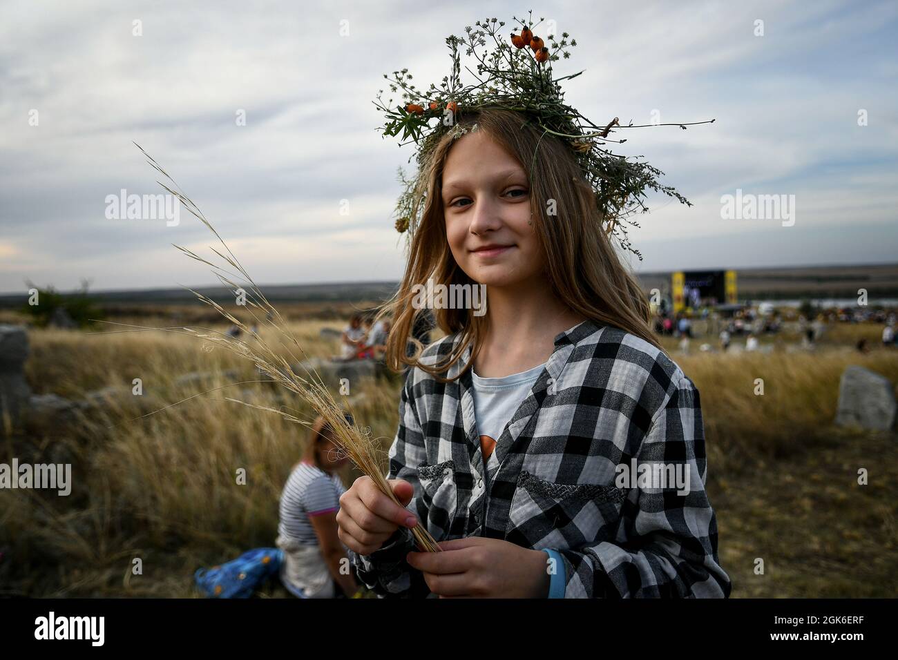 REGION ZAPORIZHZHIA, UKRAINE - 11. SEPTEMBER 2021 - Ein Mädchen in einem karierten Hemd trägt eine Krone aus Wildblumen während der Legends of Steppe 2021 Open Folk Stockfoto