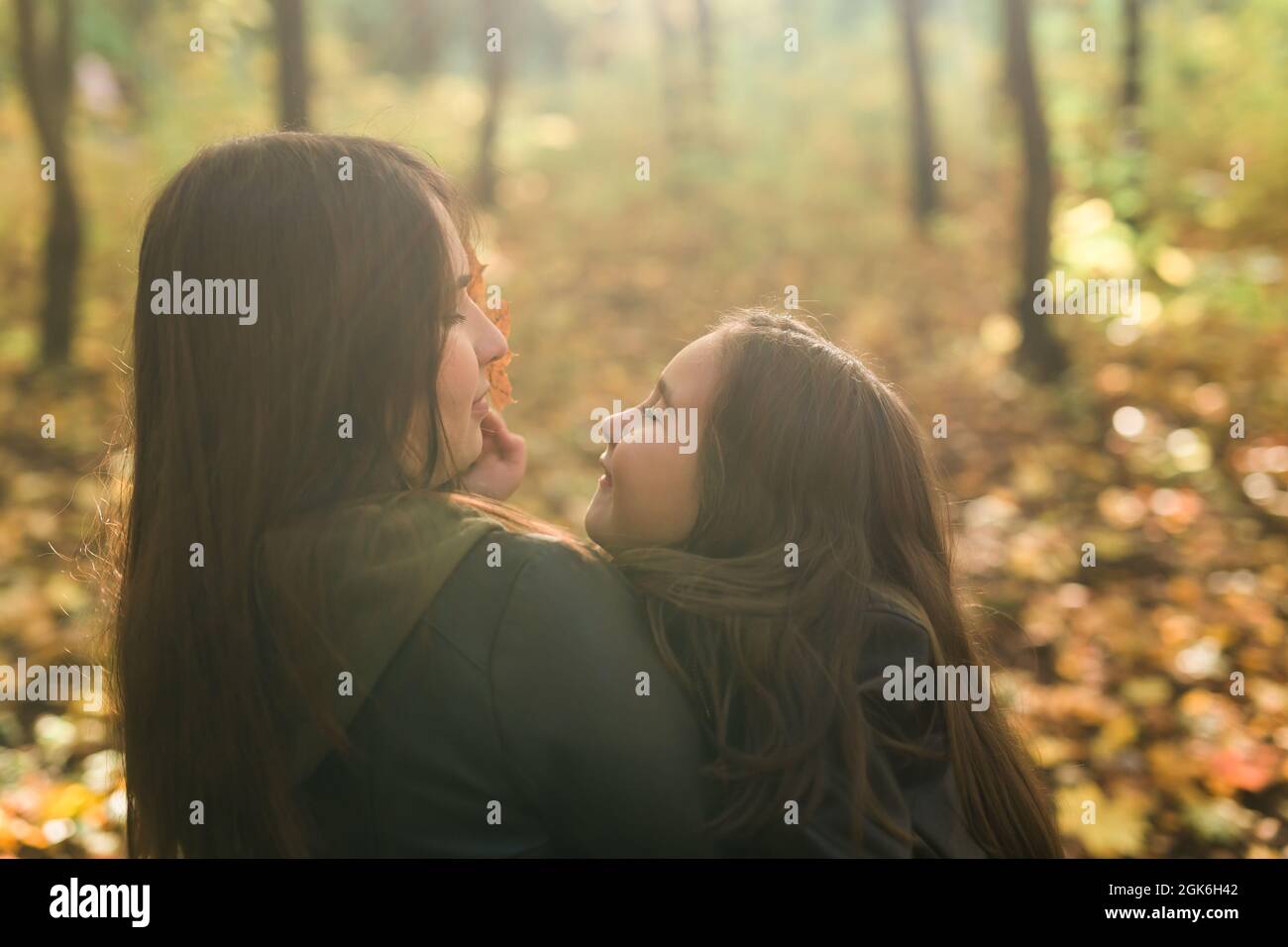 Mutter und Tochter verbringen Zeit zusammen im gelben Herbstpark. Saison- und Alleinerziehende Konzept. Stockfoto