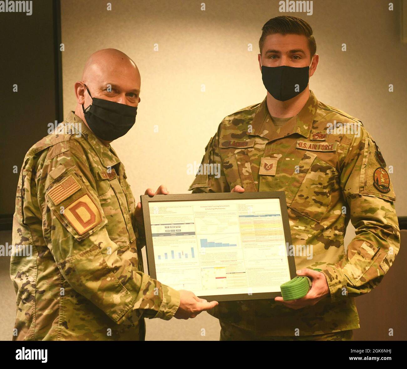 U.S. Air Force Senior Master Sgt. Stephen Holdenried, 100th Air Betanking Wing Continuous Process Improvement Process Manager, präsentiert der US Air Force Tech eine gerahmte Kopie eines Green Belt-Zertifizierungsprojekts. Sgt. Ross Kahle, 373. Trainingsgeschwader, Ablösung 19 Aerospace Ground Equipment Instructor, bei der Royal Air Force Mildenhall am 18. August 2021. Kahle initiierte das Projekt und stellte ein Team zusammen, um Probleme in seinem Ausbildungsgeschwader im Rahmen seines Zertifizierungsprozesses zu finden und zu lösen, so dass er die vollständige Zertifizierung im Green Belt Training erhalten konnte. Stockfoto