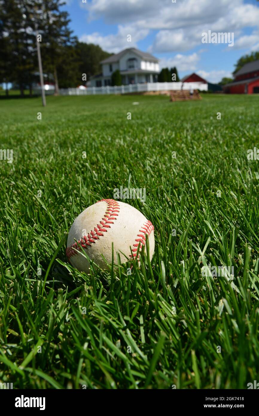 Ein Baseballspiel sitzt im Außenfeld des ehemaligen Filmset von Field of Dreams in Dyersville, Iowa. Der Fokus liegt auf dem Baseballspiel. Stockfoto