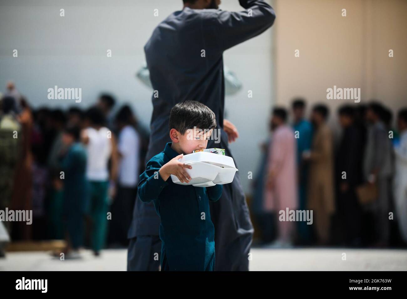 Ein afghanisches Kind trägt seinen Saft aus dem Speisesaal im CENTCOM AOR, 21. August 2021. US-Dienstmitglieder unterstützen das Außenministerium bei einer nicht-kombatanten Evakuierungsoperation (NEO) in Afghanistan. Stockfoto