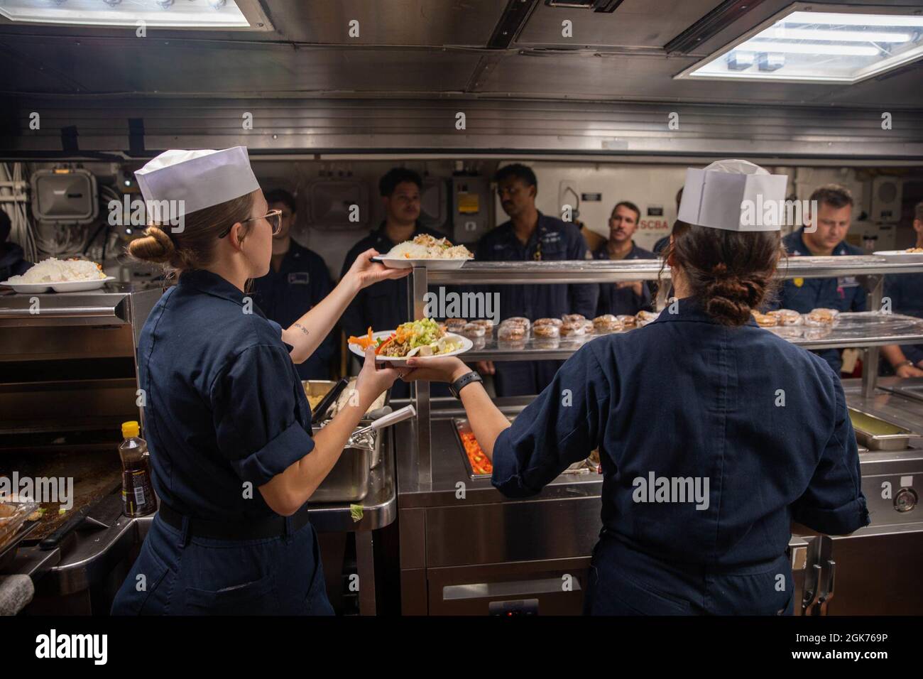 ARABISCHES MEER (Aug 21, 2021) – Seeleute bereiten während der „mongolischen Nacht“ an Bord des Lenkraketen-Zerstörers USS Halsey (DDG 97) am 21. August im Arabischen Meer Nahrung zu. Halsey wird im Einsatzgebiet der 5. US-Flotte eingesetzt, um Marinestützpunkte zu unterstützen, um die maritime Stabilität und Sicherheit in der Zentralregion zu gewährleisten und das Mittelmeer und den Pazifik durch den westlichen Indischen Ozean und drei strategische Engpässe zu verbinden. Stockfoto
