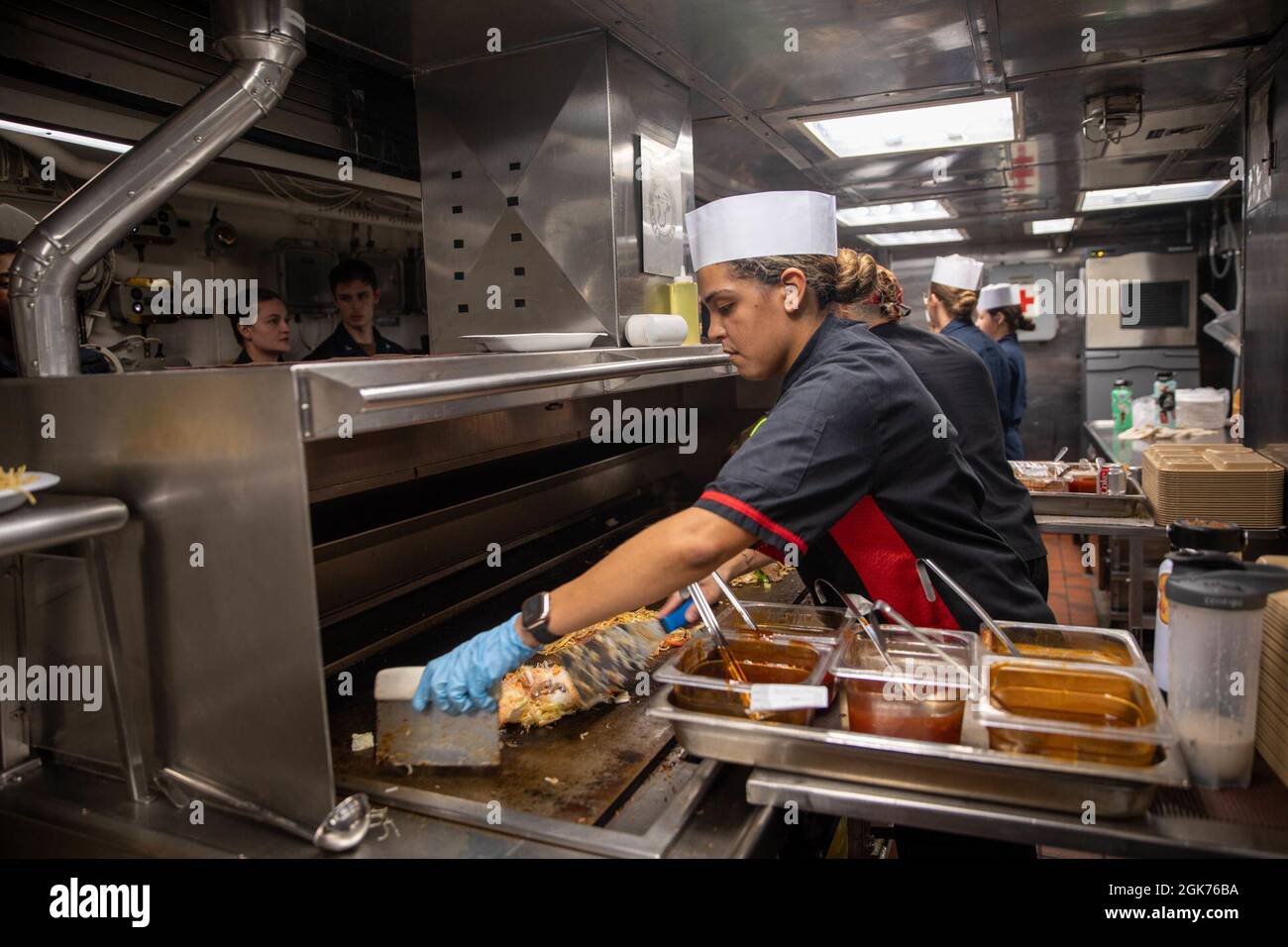 ARABISCHES MEER (Aug 21, 2021) – Seeleute bereiten während der „mongolischen Nacht“ an Bord des Lenkraketen-Zerstörers USS Halsey (DDG 97) am 21. August im Arabischen Meer Nahrung zu. Halsey wird im Einsatzgebiet der 5. US-Flotte eingesetzt, um Marinestützpunkte zu unterstützen, um die maritime Stabilität und Sicherheit in der Zentralregion zu gewährleisten und das Mittelmeer und den Pazifik durch den westlichen Indischen Ozean und drei strategische Engpässe zu verbinden. Stockfoto