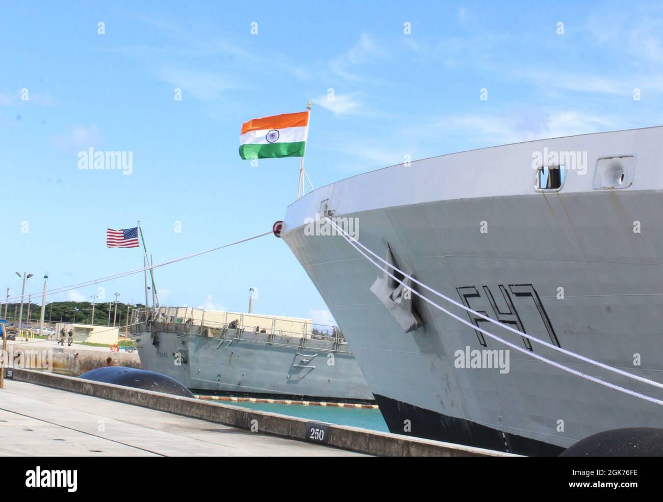SANTA RITA, Guam (Aug 23, 2021) - die amerikanische Flagge schwingt im Wind vor der USS O'Kane (DDG 77), da die indische Flagge von INS Shivalik (F47) auf dem US Naval Base Guam am am 21. August abgeflogen wird. INS Kadmatt (P29), eine Korvette gegen U-Boot-Kriegsführung, und INS Shivalik (F47), eine Shivalik-Klasse-Tarnkappenfrigate, kamen am 21. August auf dem US-Marinestützpunkt Guam an. Die beiden Schiffe sollen an der jährlichen gemeinsamen Marineübung Malabar 2021 teilnehmen. Malabar 2021 ist ein Beispiel für die dauerhafte Partnerschaft zwischen australischen, indischen, japanischen und amerikanischen Seestreitkräften, die routinemäßig zusammenarbeiten Stockfoto