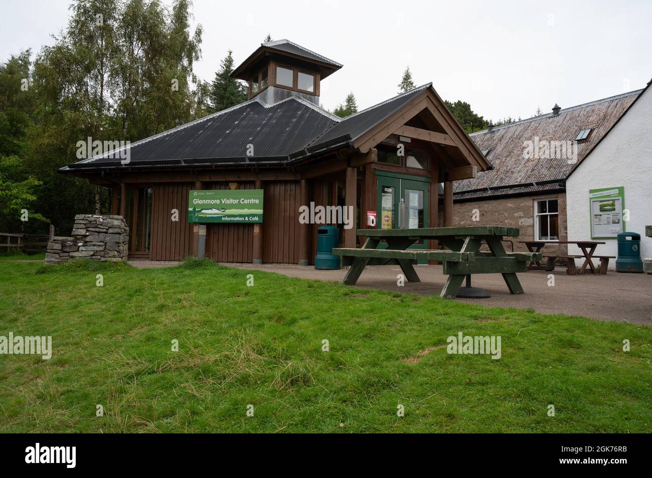 Außenansicht des Glenmore Visitor Centre im Cairngorms National Park. Holzbank vorne und Rasenfläche. Keine Personen. Wolkiger Tag. Stockfoto