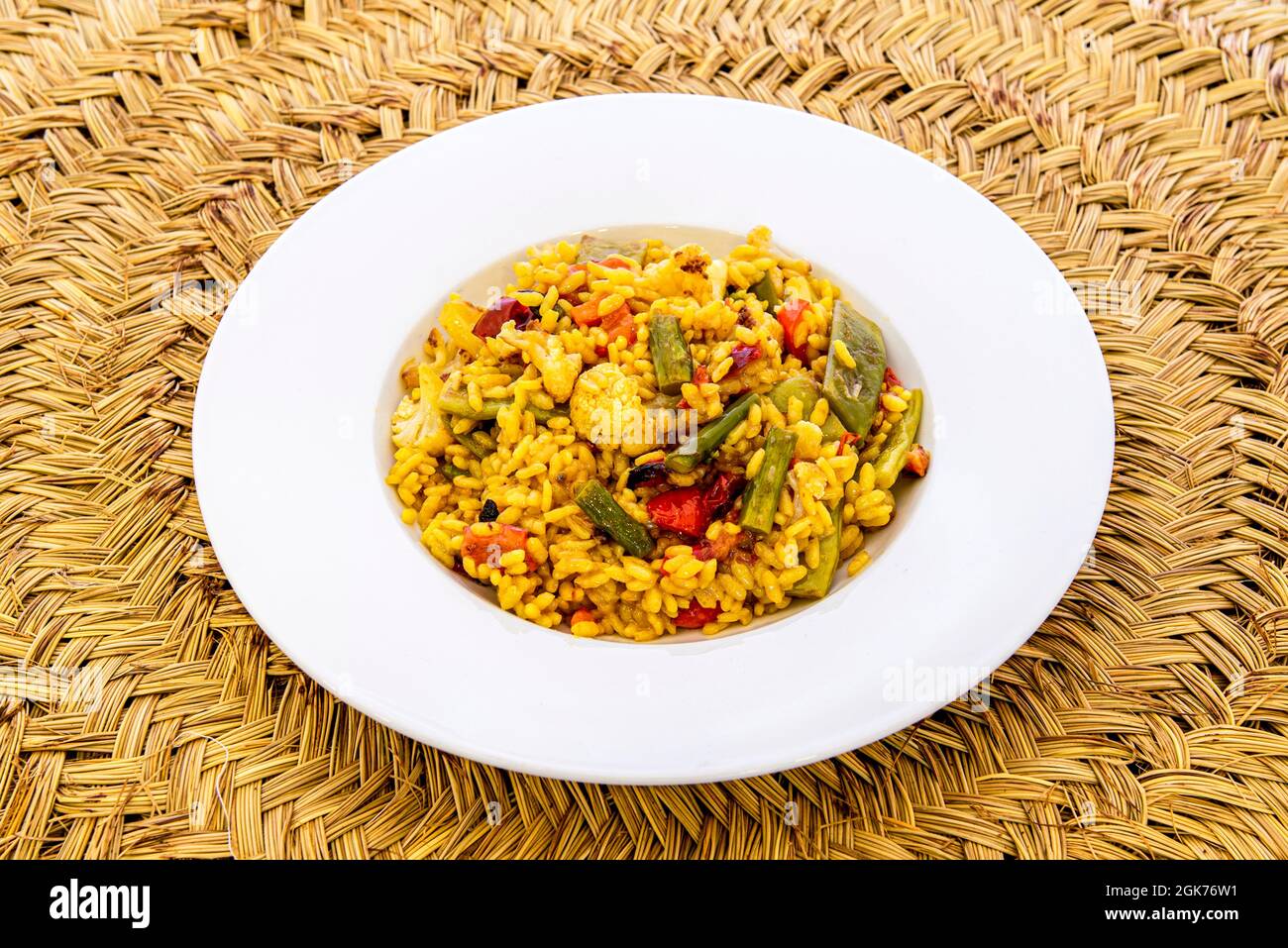 Spanische Reispaella mit Gemüse auf einem natürlichen Faser-Trivet Stockfoto