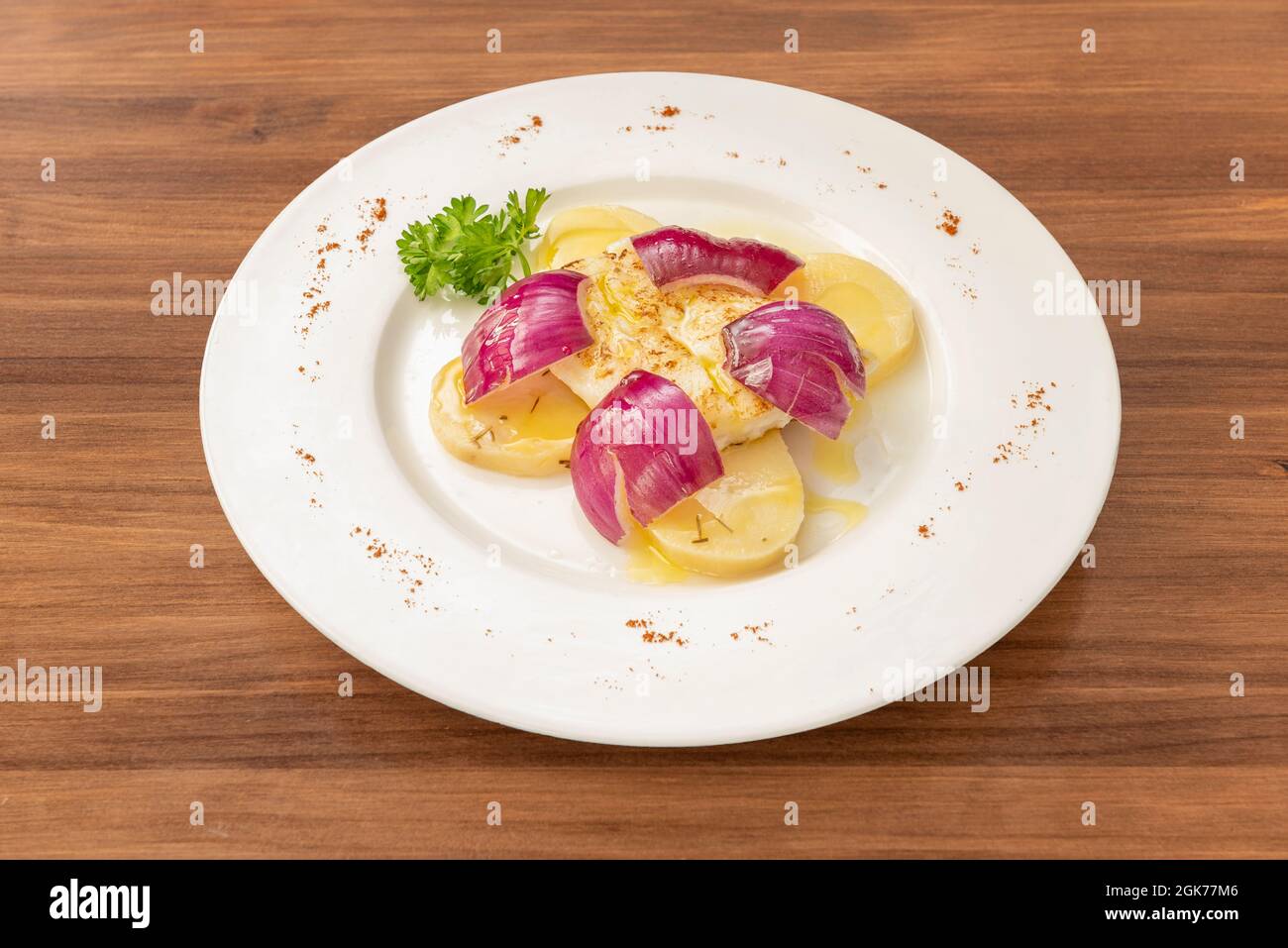 Spanisches Rezept für gegrillten Kabeljau mit gekochten Kartoffeln und roten Zwiebeln mit Olivenöl und frischer Petersilie Stockfoto