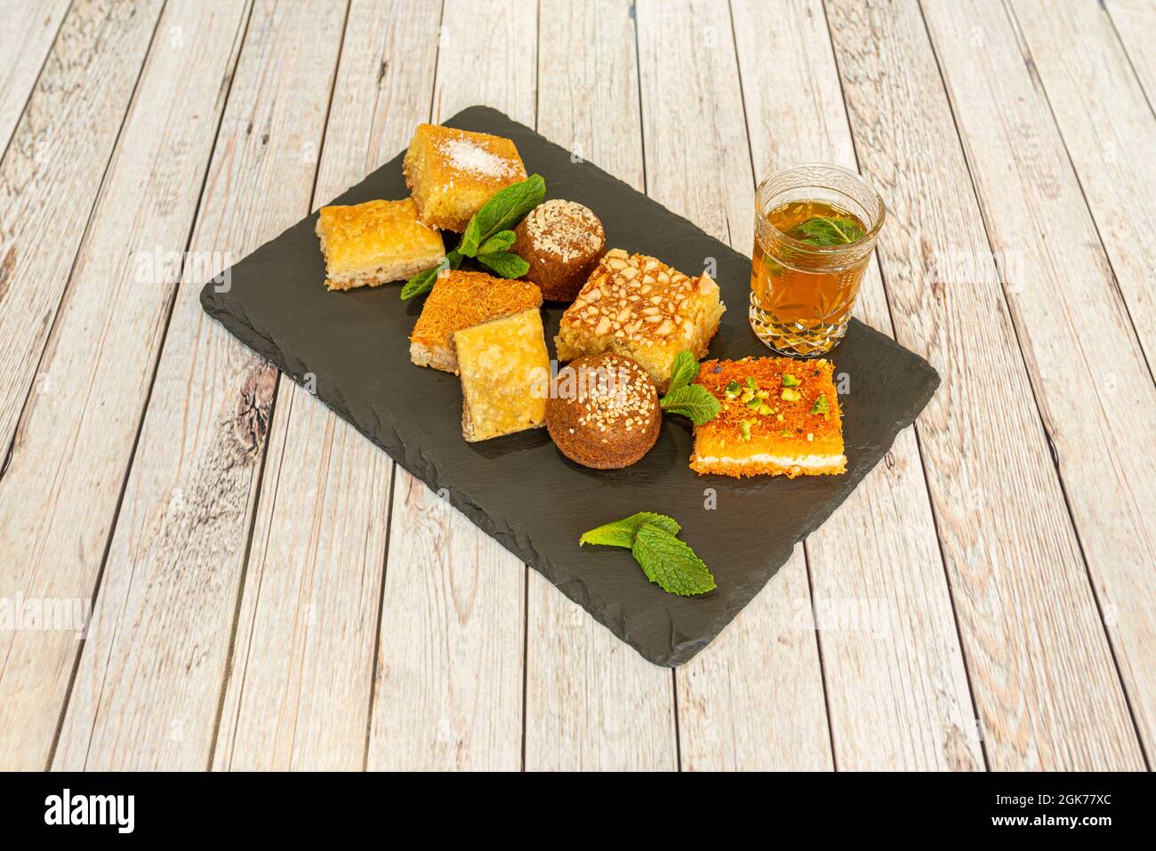 Verschiedene Arten süßer arabischer Baklava und ein Glas maurischen Tees mit Minze auf Schieferplatte Stockfoto