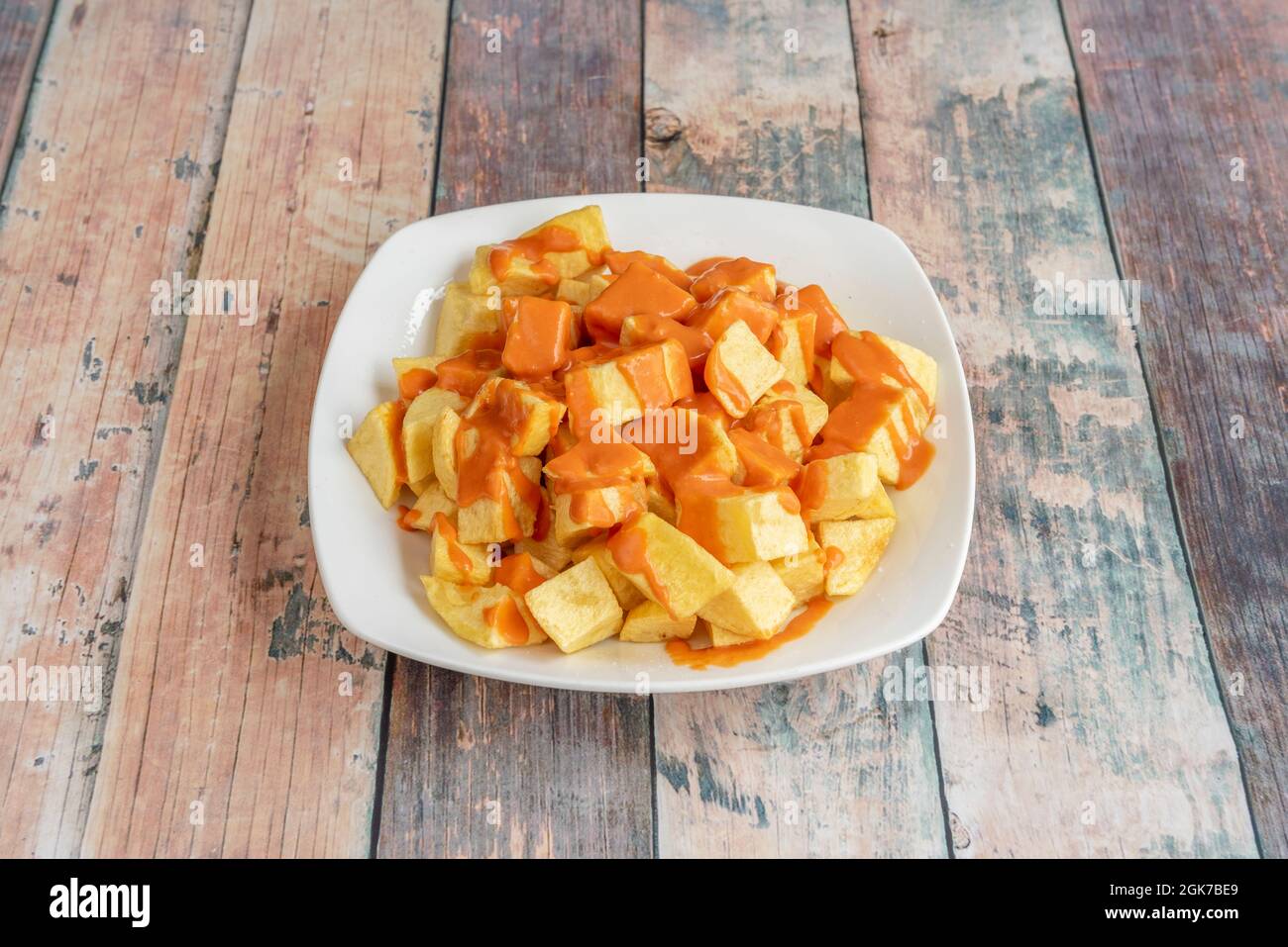 Tapas mit spanischen Patatas Bravas werden in einem beliebten Tapas-Restaurant mit Holztischen serviert Stockfoto