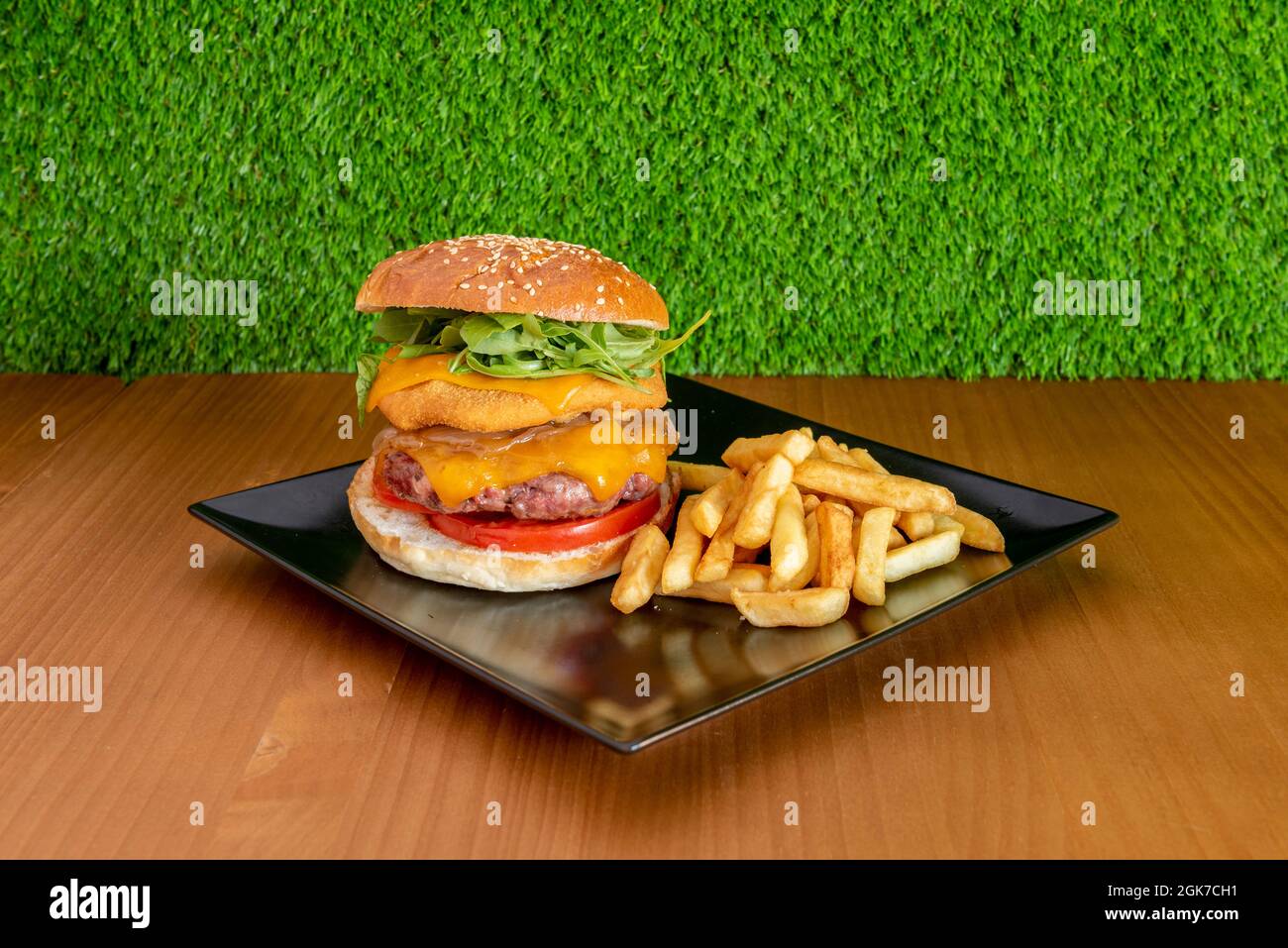 Double Mixed Beef and Chicken Burger mit Double Cheddar-Käse, Arugula, Mayonnaise und Tomatenscheiben mit Pommes frites Stockfoto