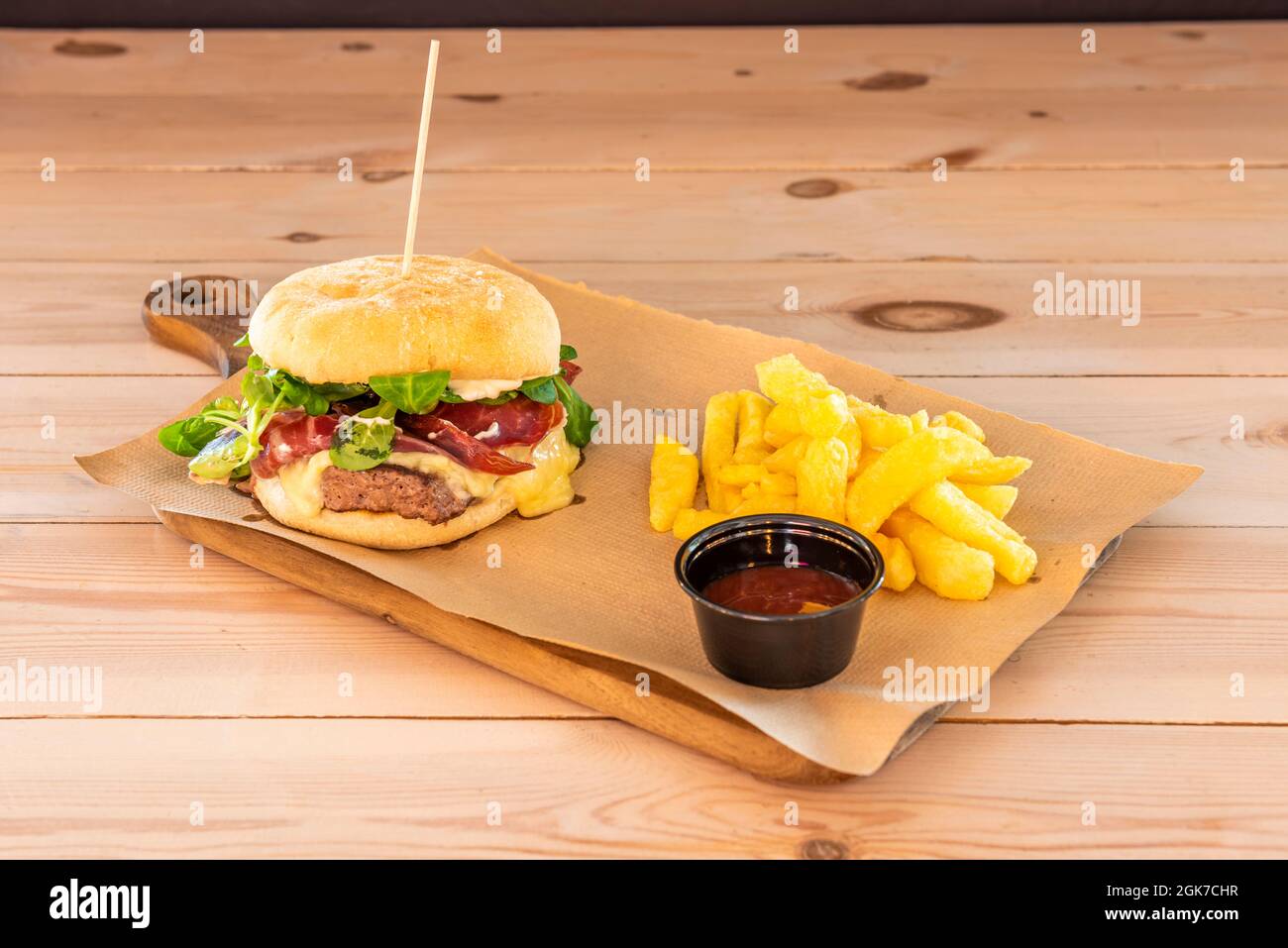 Galizischer Rindfleisch-Burger mit Jabugo-Schinken, viel geschmolzenem Käse und Lammsalat-Sprossen, garniert mit Pommes frites und Barbecue-Sauce zum Eintauchen Stockfoto