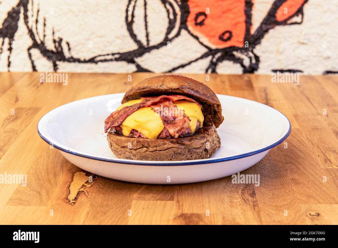 Beef Burger mit doppelt geschmolzenem Cheddar-Käse, gebratenen Bacon-Streifen und Vollkornbrot-Muffin Stockfoto