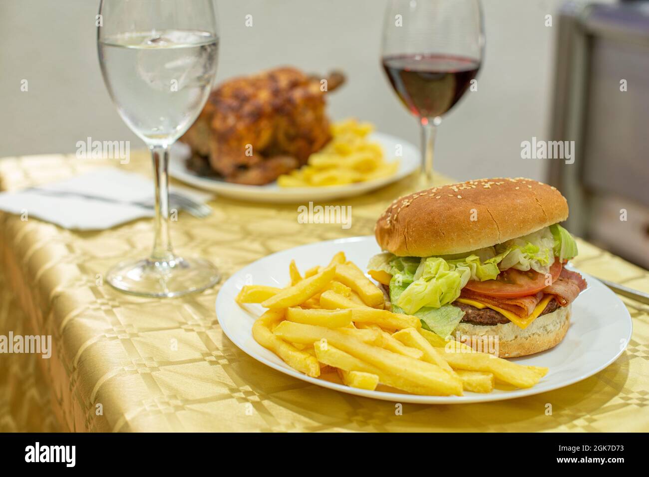 Klassischer Burger auf einem Sommermenü mit gebratenem Huhn und Pommes frites. Rinderburger mit Cheddar-Käse, gebratenem Speck, Tomaten und Salat, Ketchup und Senf Stockfoto