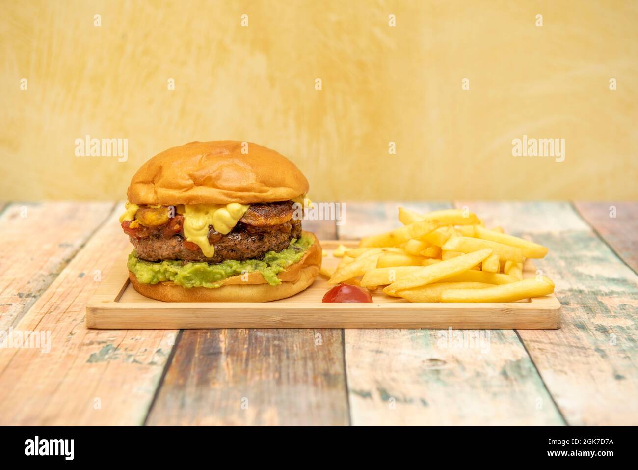 Double Burger im mexikanischen Stil mit Guacamole mit Cheddar-Käse und jalapeños garniert mit Pommes, Ketchup und Senf Stockfoto