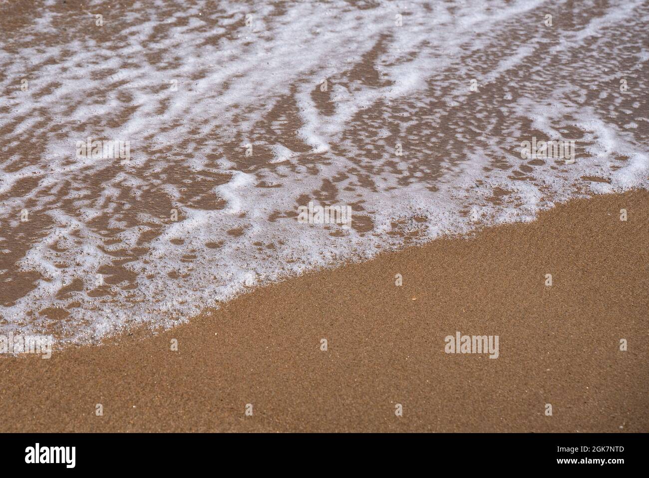 Ocean Nature-Bild mit Nahaufnahme von Details wie schaumiges Wasser, während die Wellen am Strand an der Küste aufspühlen Stockfoto