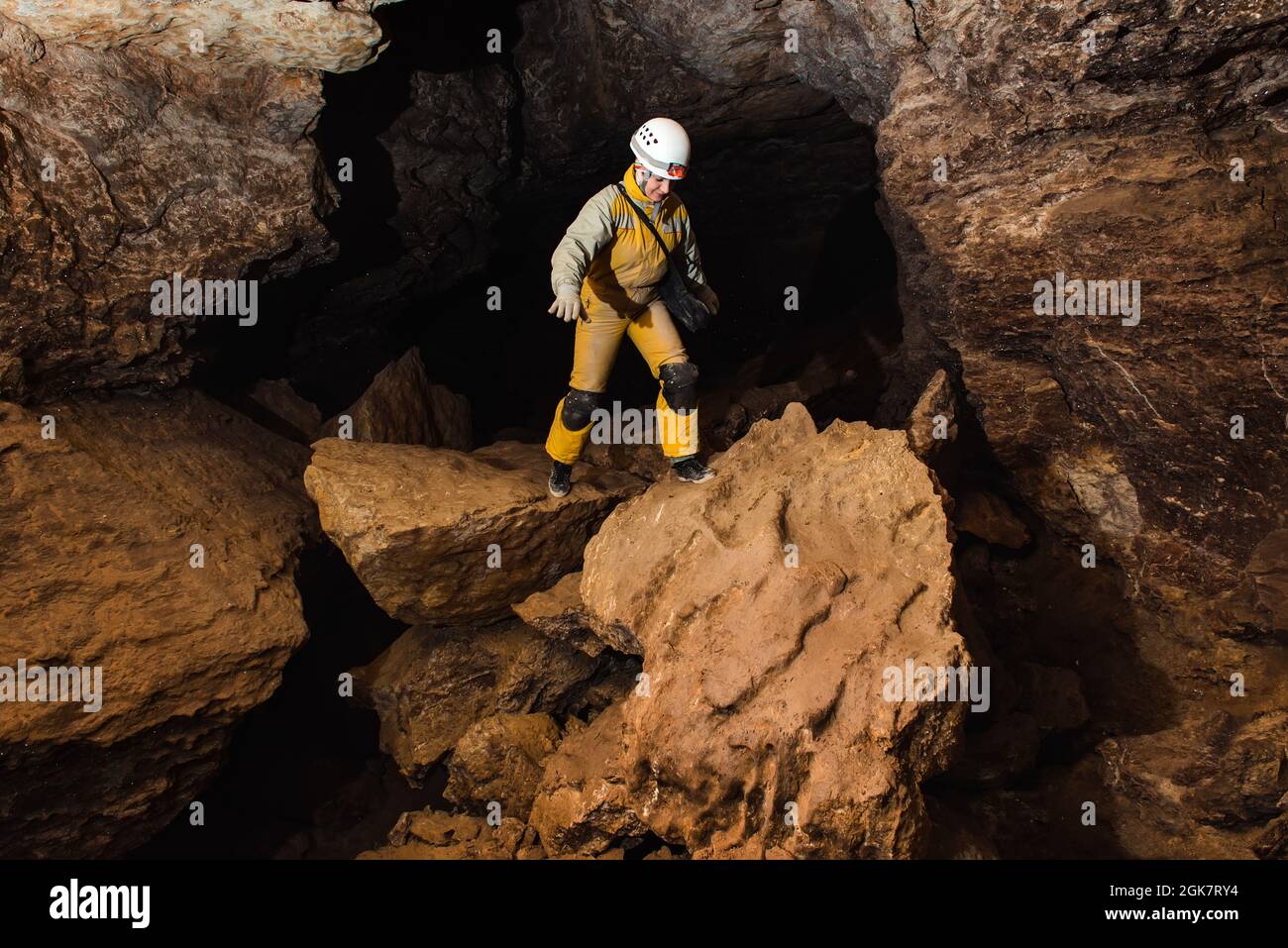 Tourist in Schutzanzug und Helm mit Taschenlampe erkundet die Höhle. Extrem aktiver Sport Stockfoto