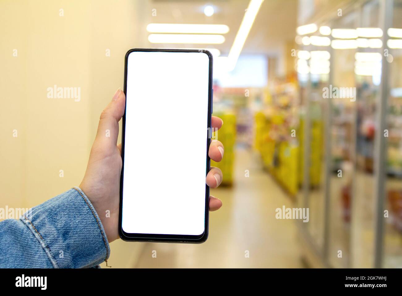 Mockup Bild von Frau Hand hält weißen Desktop-Bildschirm Handy im Supermarkt. Stockfoto