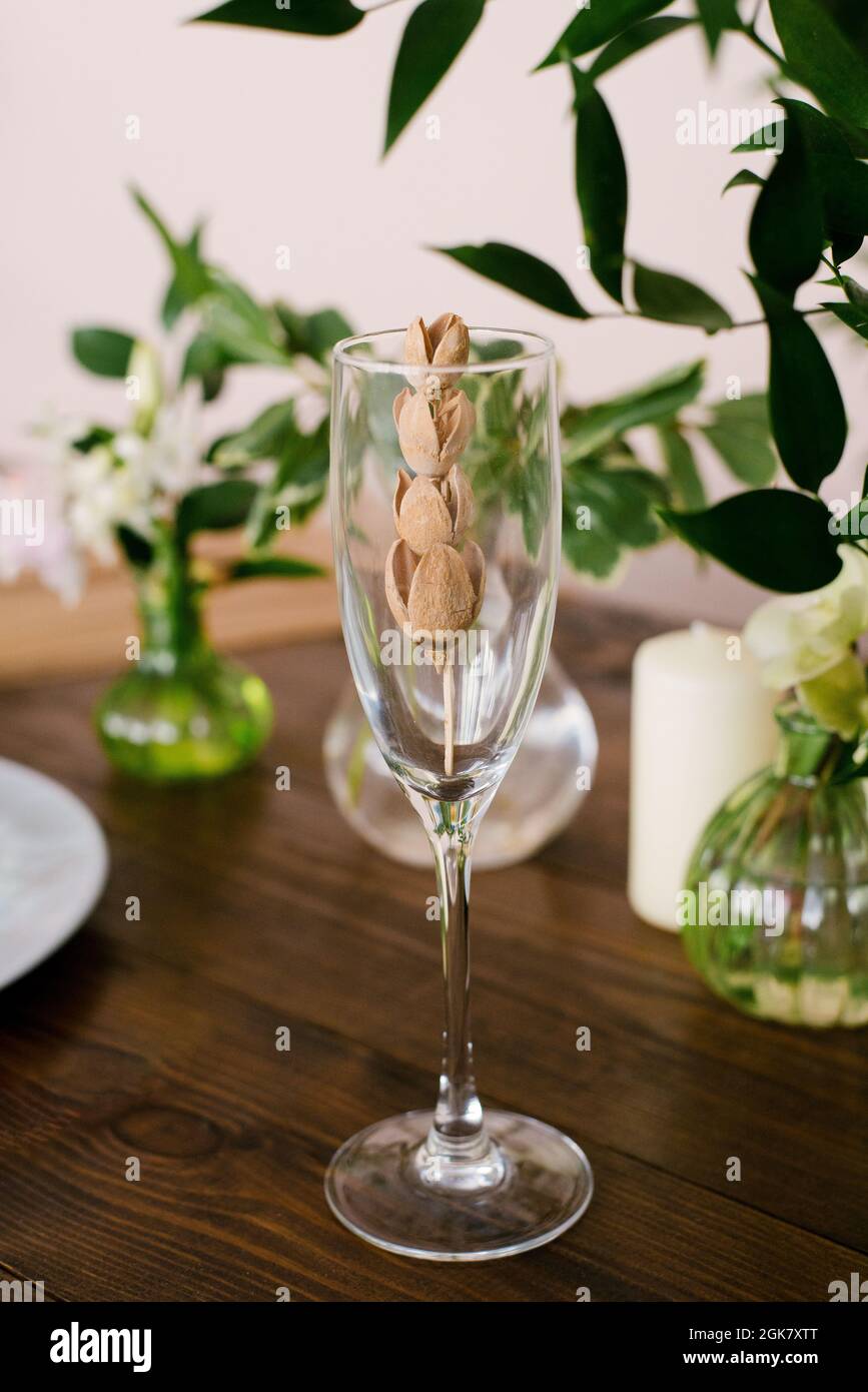 Elegante, stilvolle Einrichtung eines festlichen Tisches oder Innenraums. Getrocknete Blume in einem Glas Champagner Stockfoto