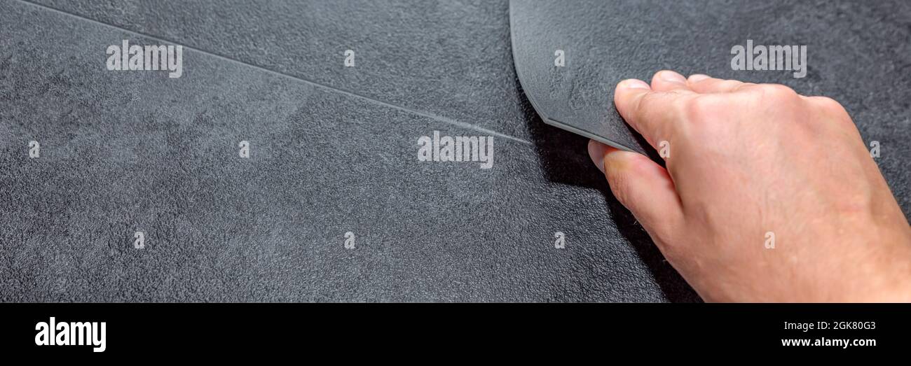 Verschiedene Böden. Renovierungs- oder Baukonzept. Nahaufnahme einer männlichen Hand, die eine strukturierte Bodenplatte aus Vinyl hält. Proben von Laminat und Vinyl Stockfoto