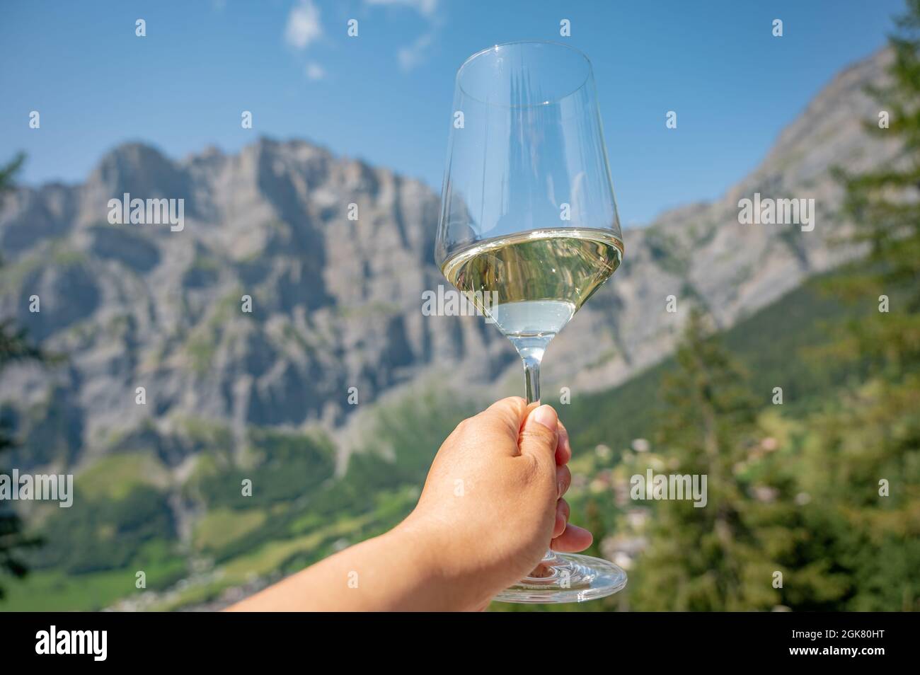 Hand hält ein Glas Wein. Hintergrund von Berg und Himmel. Glücklicher Lebensstil. Stockfoto