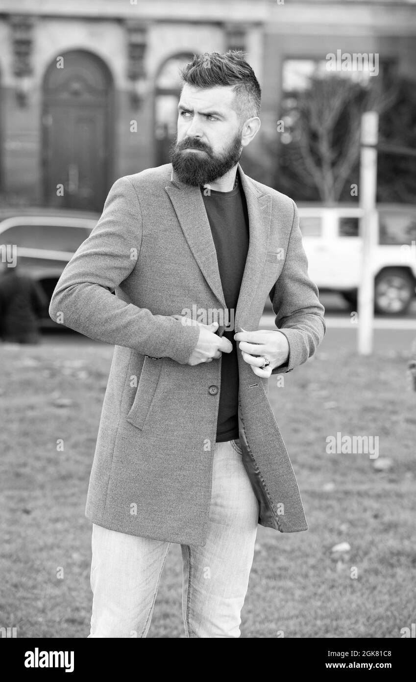 Brutal reifer bärtiger Mann mit Schnurrbart, der im Freien in einer trendigen, modernen Freizeitjacke im perfekten Stil unterwegs ist Stockfoto