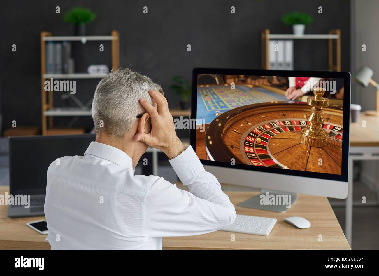 Unglücklicher Spieler spielt ein Online-Casino-Spiel auf seinem Computer und verliert sein ganzes Geld Stockfoto