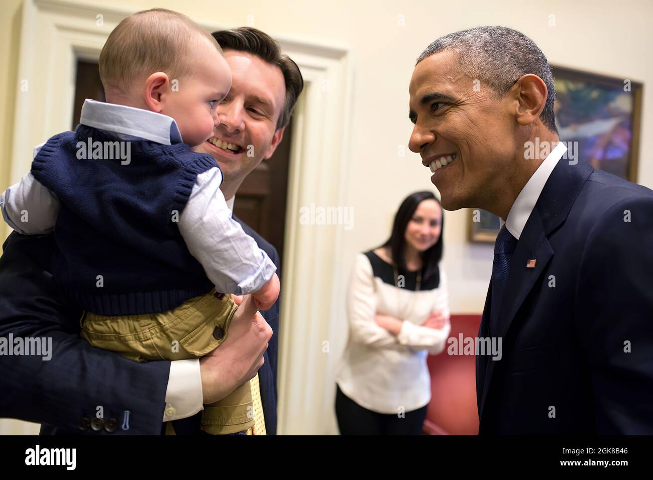 Präsident Barack Obama begrüßt Pressesprecher Josh Earnest und seinen Sohn Walker Natalie Wyeth, die Frau von Earnest, sieht ernsthaft im Oval Office am 20. März 2015 zu. (Offizielles Foto des Weißen Hauses von Pete Souza) Dieses offizielle Foto des Weißen Hauses wird nur zur Veröffentlichung durch Nachrichtenorganisationen und/oder zum persönlichen Druck durch die Betreffzeile(en) des Fotos zur Verfügung gestellt. Das Foto darf in keiner Weise manipuliert werden und darf nicht in kommerziellen oder politischen Materialien, Anzeigen, E-Mails, Produkten oder Werbeaktionen verwendet werden, die in irgendeiner Weise eine Zustimmung oder Billigung des Presi nahelege Stockfoto