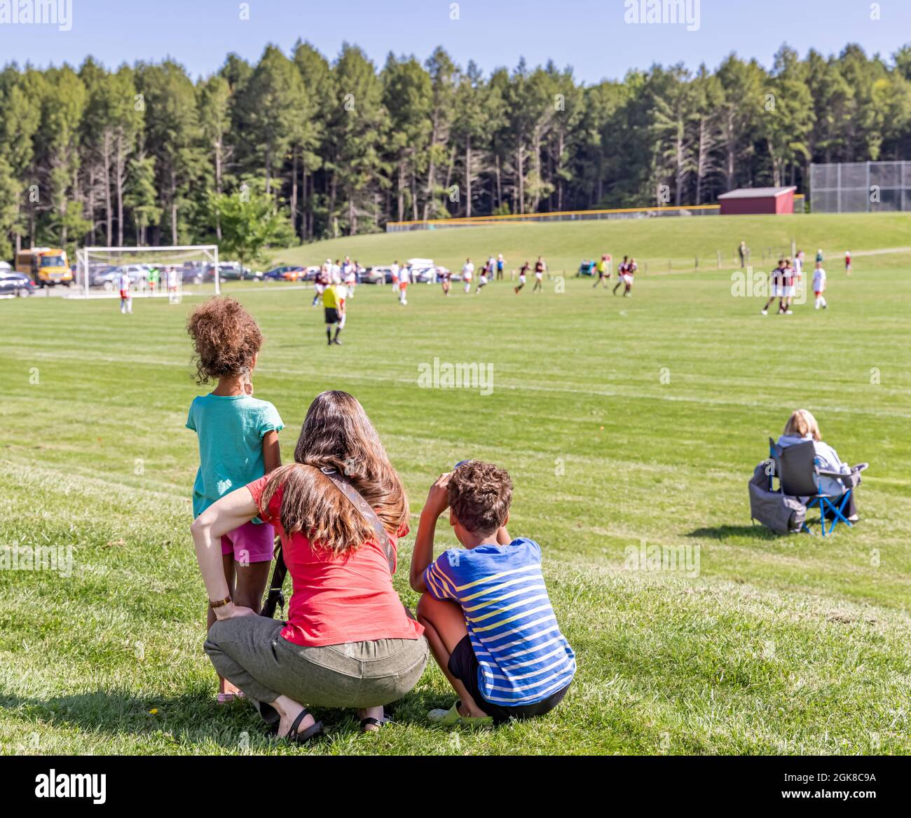 Mutter mit zwei kleinen Kindern, die ein Fußballspiel beobachten Stockfoto