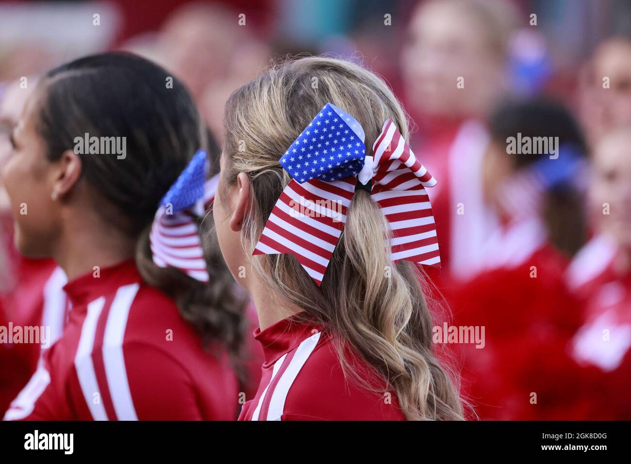 BLOOMINGTON, UNITED STATES - 2021/09/11: Cheerleader der Indiana University tragen am Jahrestag des Jahres 9/11 amerikanische Fahnenbänder im Haar, bevor die IU während eines NCAA-Fußballspiels am 11. September 2021 im Memorial Stadium in Bloomington, Ind., gegen die Vandals 56-14 spielt. Stockfoto